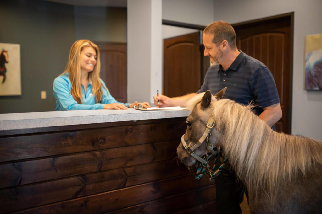 A man and his miniature horse sign-in at the reception desk.